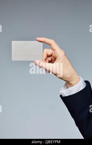 Close up of female hand holding business card mockup to camera against grey background Stock Photo