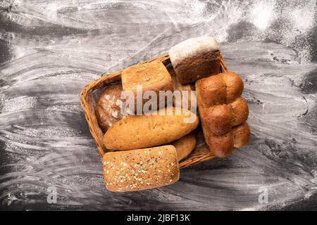 Basket with fresh bread on table against black background. Bakery products in straw basket isolated Stock Photo