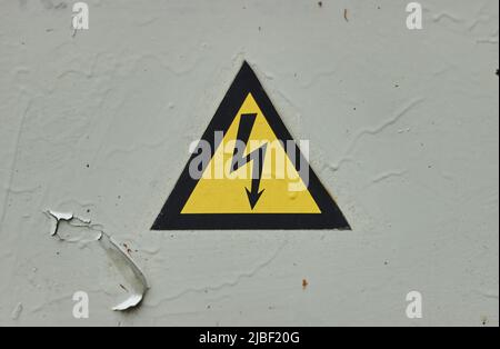Close up of old Grey Hinged Power Supply Box with yellow danger warning sign electricity in remote places Stock Photo