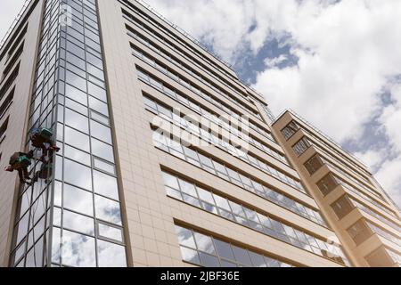 two men cleaning windows on a high rise building Stock Photo