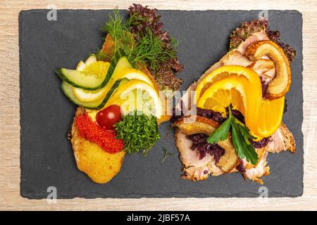 Smørrebrøds, traditional Scandinavian sandwiches, with breaded sole fillet fried in butter, black rye bread, roast pork and roast pork rind. Denmark, Stock Photo