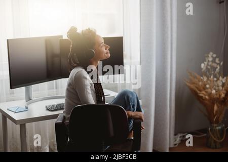 Side view of happy young woman listening to music in black headphones, leisure concept Stock Photo
