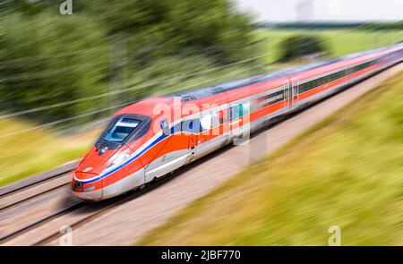 A Frecciarossa (ETR 1000) high speed train from italian rail company Trenitalia is driving at full speed in the countryside. Stock Photo