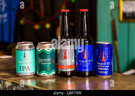 Five Segull 67 beers stand side by side on the bar of the Segull 67 brewery in Siglufjörður, northern Iceland: the cans "Naggur IPA" and "Sjarmör Icelandic Craft Lager", plus bottles and cans of the "Siglo IPA" and "Original" varieties. The small family-run brewery is housed in a former fish factory and belongs to the Independent Craft Brewers of Iceland (ICBI). Its name combines "segull", Icelandic for magnet, with 67, the lucky number of founder Marteinn B. Haraldsson's family. A compass's magnetic needle is part of the logo. Stock Photo