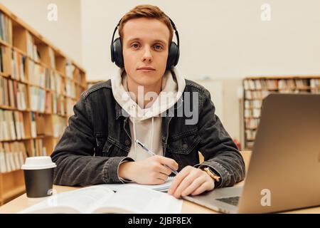 Handsome male student in a university library. Young man studying on school assignment. Stock Photo