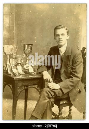 Original Studio portrait photograph of nice looking confident teenage boy at King Edward V1 Five Ways Grammar School (K.E.G.S) with prizes - there is a large silver cup dated 1911 and lots of other medals and cups.  Bartley Green, Birmingham, West Midlands, England, U.K. Circa 1914 Stock Photo