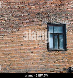 An abandoned old window in a dirty red brick wall Stock Photo
