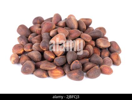 Pine nuts isolated on white background. Pine cones and heap of roasted pine nuts in shells. Stock Photo