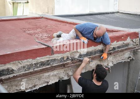 Two masons removing old metal beams in a construction house. Stock Photo