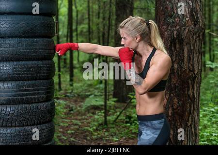 Woman boxer doing cross kick working out outdoors. Stock Photo