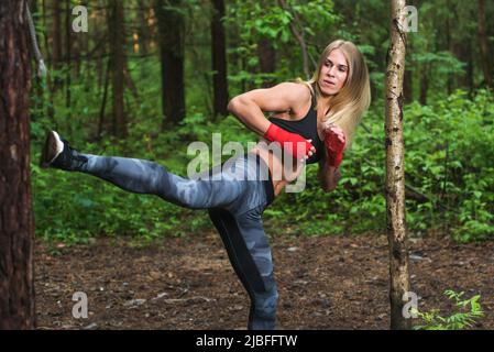 Fit woman doing kickboxing training, exercising, working out outdoors. Stock Photo