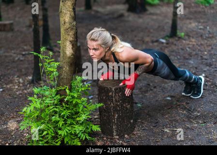 Muscular woman doing push-ups at park street work out. Stock Photo