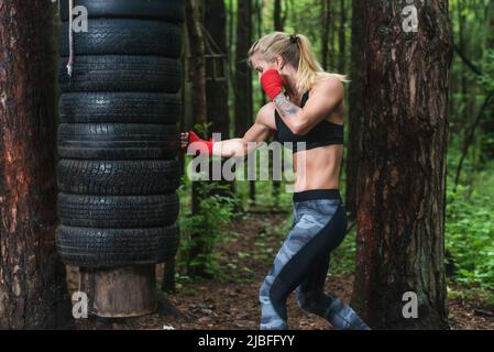 Woman boxer doing uppercut kick working out outdoors Stock Photo