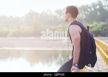 Young man runner resting after workout session on sunny morning. Stock Photo