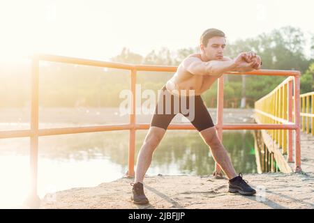 Young sporty man bending forward and doing stretching exercise Stock Photo
