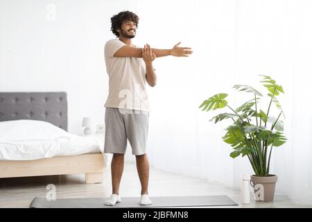 Cheerful indian man practicing yoga at home Stock Photo