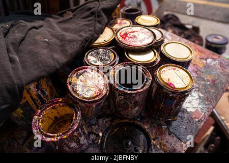 From above of messy metal cans with colorful paints placed on wooden table on street of Tainan Stock Photo