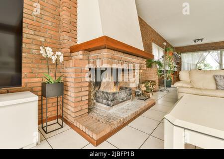 Fireplace with orchids flower pots located in light living room with comfortable sofas Stock Photo