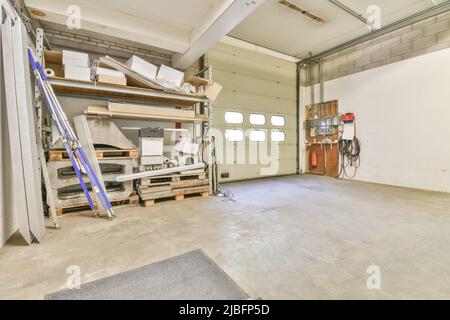 Stack of wooden pallets and cardboard boxes on shelves on spacious warehouse in industrial area in daylight Stock Photo