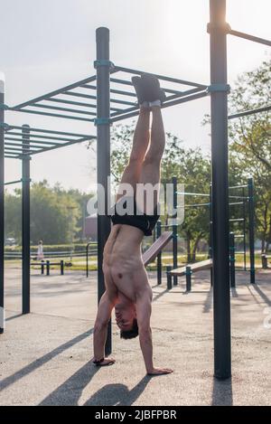 Young fit muscular man doing handstand Workout outdoors. Stock Photo