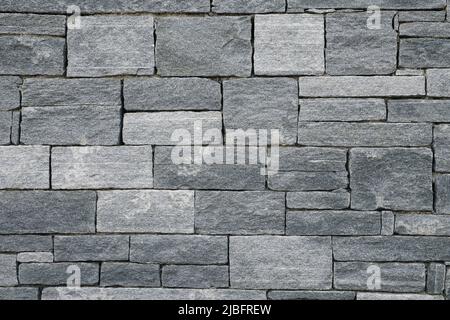 Big and small Bricks in a grey Stone Wall Stock Photo