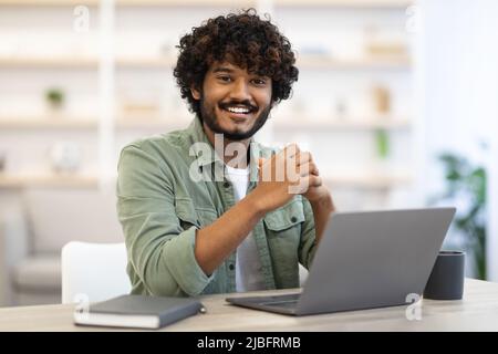 Cheerful indian guy programmer posing at workdesk Stock Photo
