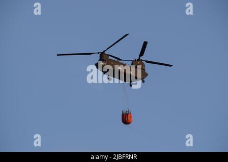 A firefighting Chinook helicopter operates in the region of Voula  southern suburb, as wildfire blazes threatening surrounding homes. Athens, Greece, 4 June 2022. Credit: Dimitris Aspiotis / Alamy Stock Photo