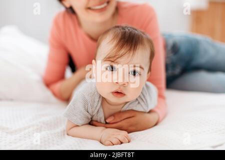 Closeup portrait of cute little kid, mom helping her crawl on bed in bedroom at home Stock Photo