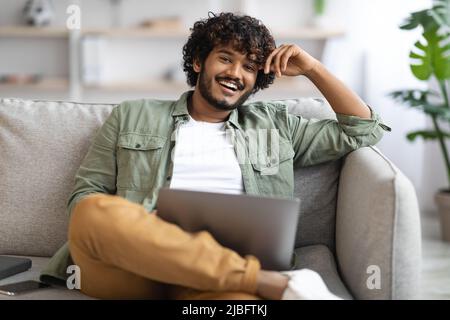 Happy indian guy using notebook at home Stock Photo