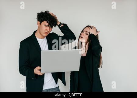 Two people working on laptop, problems, depressed, upset and puzzled by results. Standing on white background Stock Photo