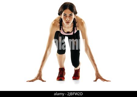 Front camera view of young female runner getting ready to run isolated on white studio background. Sport, track-and-field athletics, competition Stock Photo
