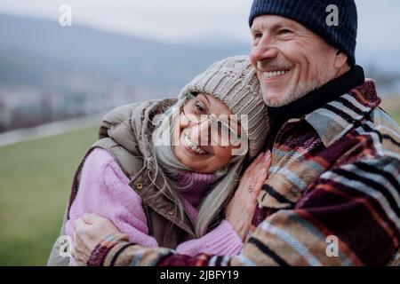 Senior man hugging and consoling his wife outdoors in garden in winter. Stock Photo