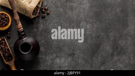 Turkish coffee background with copy space. Cezve pot, overturned bag and spatula full of roasted beans Stock Photo