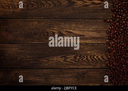Coffee beans on table brown wood. Abstract wooden board background and roasted aromatic seeds border. Coffeehouse concept Stock Photo