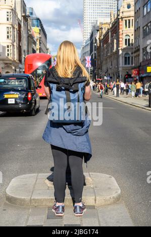 LONDON - May 18, 2022: Blonde female photographer photographing a busy London Street Stock Photo