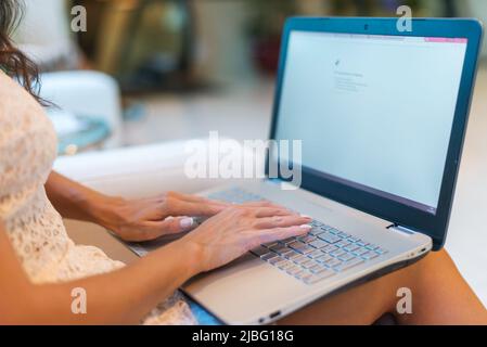 Female hands on keyboard with opened web page in browser at screen. Cropped image of woman surfing the internet on her laptop Stock Photo