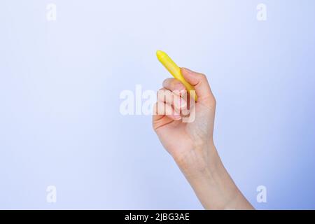 Hand holding chalk on isolated white background. Woman writing something with yellow chalk. Stock Photo