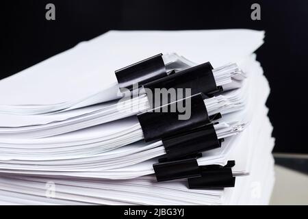 A stack of office papers, some of which are fastened with black binders Stock Photo