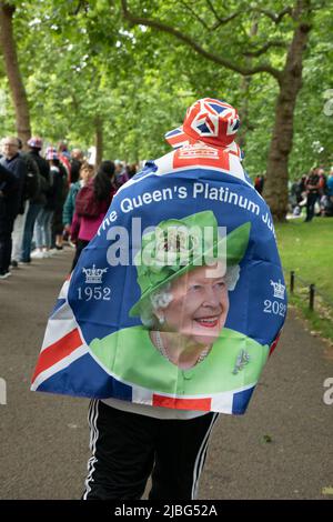 London, UK. 5th June 2022. A man has a flag depicting the Queen draped over his shoulders as the 7-thousand-people strong Platinum Jubilee Pageant was held in central London to mark her Majesty's 70 years on the throne. The colourful parade made its way along Whitehall, the Mall and past Buckingham Palace and was described by many as a once in a lifetime event. Credit: Kiki Streitberger / Alamy Live News Stock Photo