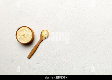 Cheese sauce in wooden bowl with spoon on cement background. Top view with copy space. Stock Photo