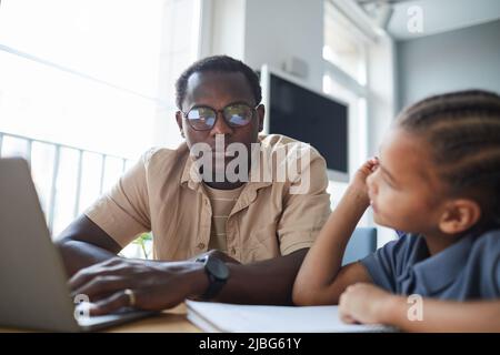 Portrait of caring black father working from home and looking at cute daughter drawing by his side Stock Photo