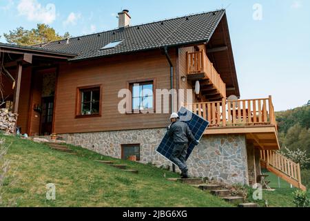 Man worker carrying solar panel for installing solar modul system on house. Stock Photo