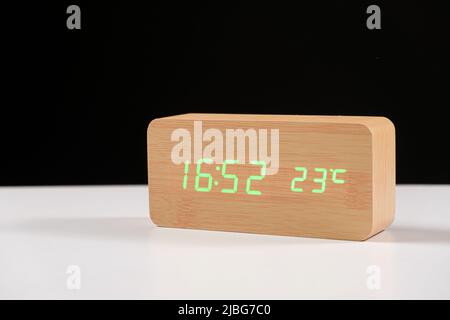 Electronic wooden clock with thermometer on black and white background close-up with space for text Stock Photo