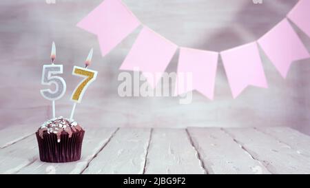 Birthday number. Festive background for a girl or woman with a muffin and candles burning pink in pastel colors with decorations for any holiday, Stock Photo