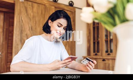 Smiling young girl purchases online using phone Stock Photo