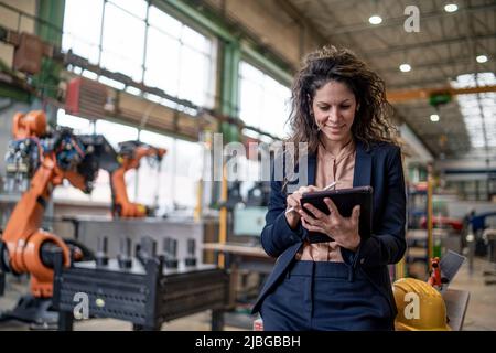 Portrait of female chief engineer in modern industrial factory using tablet. Stock Photo
