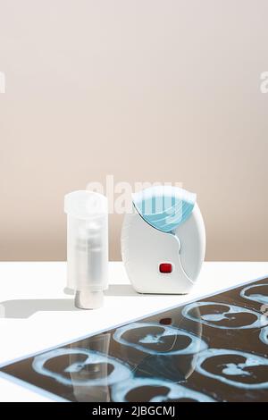 Some asthma inhalers and CT scan of the lungs on white table. Aerosol for inhalation for treat lung inflammation and prevent asthma attack. Stock Photo