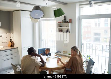 Wide angle scene on multiethnic family at dinner table in kitchen, copy space Stock Photo