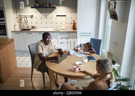 High angle home scene of modern multiethnic family at dinner table in kitchen, copy space Stock Photo