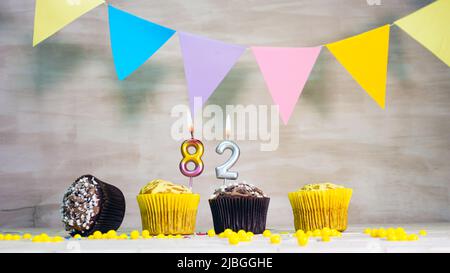 Birthday background with number. Beautiful birthday card with colorful garlands, a muffin with a candle burning copyspace. Stock Photo